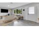 Comfortable living room features large windows, modern furnishings, light gray walls, and a stylish jute rug at 3857 Woodrow Ridge St, Sarasota, FL 34233