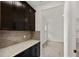 Butlers pantry with dark cabinets, quartz countertop, and decorative backsplash leading to a bright adjacent room at 4240 Pond Brook Ct, Bradenton, FL 34211