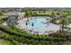 Community pool area with sun loungers, tables, umbrellas and palm trees at 4240 Pond Brook Ct, Bradenton, FL 34211