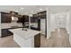 Open-concept kitchen featuring dark wood cabinets, stainless steel appliances, a large island, and wood-look tile flooring at 4240 Pond Brook Ct, Bradenton, FL 34211