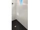 Modern shower with black honeycomb tile flooring, white tiled walls, and a small window at 4240 Pond Brook Ct, Bradenton, FL 34211