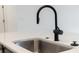 A close-up on a stainless steel kitchen sink featuring a sleek black faucet and white countertops at 4240 Pond Brook Ct, Bradenton, FL 34211