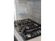 Close-up of a stainless steel gas stovetop with sleek black grates and metallic knobs at 4240 Pond Brook Ct, Bradenton, FL 34211