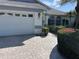 Two-car garage with brick paved driveway and lush landscaping with flowering bushes at 4538 Hamlets Grove Dr, Sarasota, FL 34235