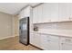 Modern kitchen with stainless steel refrigerator, white cabinets, and wood-look tile flooring at 5307 Senza Trl, Palmetto, FL 34221