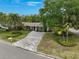 Beautifully landscaped home featuring a gray brick driveway and lush tropical foliage at 577 Corwood Dr, Sarasota, FL 34234
