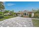 Single-story home with block driveway surrounded by lush lawn and tropical trees at 577 Corwood Dr, Sarasota, FL 34234