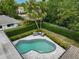 Aerial view of a uniquely shaped pool with gray-toned brick, trimmed hedges, and outdoor furniture at 577 Corwood Dr, Sarasota, FL 34234