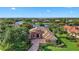 Aerial view showcasing a stunning red tile roof home with lush landscaping and tranquil lake views at 7580 Preservation Dr, Sarasota, FL 34241