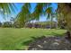 Large grassy backyard featuring palm trees and lush landscaping surrounding a screened-in lanai at 7580 Preservation Dr, Sarasota, FL 34241