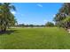 Expansive backyard with lush green lawn, mature trees, and serene lake views in a desirable community at 7580 Preservation Dr, Sarasota, FL 34241
