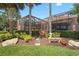 Charming backyard screened-in lanai with stepping stone pathway, lush landscaping, and a cozy patio set at 7580 Preservation Dr, Sarasota, FL 34241