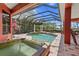 A screened-in outdoor pool with a small water feature and clear blue water is surrounded by brick tile at 7580 Preservation Dr, Sarasota, FL 34241