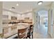An open kitchen with granite countertops, white cabinets, stainless steel appliances and a bar overlooking the living room at 808 3Rd W Ave # 214, Bradenton, FL 34205