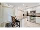An open kitchen with granite countertops, white cabinets, stainless steel appliances and a bar near the front door at 808 3Rd W Ave # 214, Bradenton, FL 34205