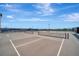 A rooftop tennis court featuring a gray surface, white lines, black net and fencing under a blue sky with some clouds at 808 3Rd W Ave # 214, Bradenton, FL 34205