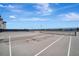 A rooftop tennis court featuring gray surface, white lines, black net and fencing under a blue sky with some clouds at 808 3Rd W Ave # 214, Bradenton, FL 34205