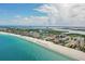 Expansive aerial view showcases a coastal community, turquoise water, sandy beach, and nearby buildings at 845 Benjamin Franklin Dr # 104, Sarasota, FL 34236