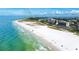 Breathtaking aerial view of a white sand beach, turquoise waters, and beachfront buildings under a cloudy sky at 845 Benjamin Franklin Dr # 104, Sarasota, FL 34236
