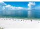 Aerial shot of a white sand beach with clear blue waters and scattered umbrellas at 845 Benjamin Franklin Dr # 104, Sarasota, FL 34236