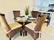 A dining area showcases a round glass table, four wicker chairs, and decor enhancing the inviting atmosphere at 845 Benjamin Franklin Dr # 104, Sarasota, FL 34236