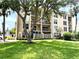 Multi-story condo building with balconies, lush green lawn, and mature trees at 845 Benjamin Franklin Dr # 104, Sarasota, FL 34236