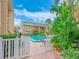 View of community pool surrounded by brick pavers, lush landscaping and a white picket fence at 845 Benjamin Franklin Dr # 104, Sarasota, FL 34236
