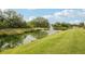 Scenic view of a community pond featuring a fountain, lush green lawn, and mature trees at 8600 Milestone Dr, Sarasota, FL 34238