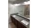 Bathroom featuring double granite vanity sinks, a large mirror, and a glass-enclosed shower at 10668 Lake Montauk Dr, Riverview, FL 33578
