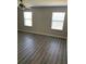 Minimalist bedroom with wood floors, two windows offering natural light, and a neutral color palette creating calm at 10668 Lake Montauk Dr, Riverview, FL 33578