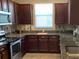 A kitchen featuring granite countertops, stainless steel appliances, and dark wooden cabinets with ample storage space at 10668 Lake Montauk Dr, Riverview, FL 33578