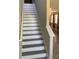 Interior staircase featuring gray wood-look steps and white risers with a view of the hallway and living area at 10668 Lake Montauk Dr, Riverview, FL 33578