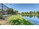 Scenic lakefront home exterior, showcasing lush green lawn and a private screened-in pool area at 12041 Thornhill Ct, Lakewood Ranch, FL 34202