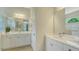 Bright bathroom featuring double sinks, white cabinets, and a view to the gardens at 12041 Thornhill Ct, Lakewood Ranch, FL 34202