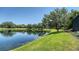 Scenic lake view with lush green lawn and mature trees at 12041 Thornhill Ct, Lakewood Ranch, FL 34202