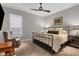 Inviting bedroom with a metal frame bed, neutral decor, and a cozy chair near a window with plantation shutters at 15024 Castle Park Ter, Lakewood Ranch, FL 34202