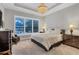 Bright bedroom with large window, plantation shutters, and neutral decor, featuring a tray ceiling and elegant chandelier at 15024 Castle Park Ter, Lakewood Ranch, FL 34202