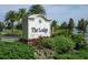 Close up of The Lodge sign surrounded by lush greenery, flowers and palms on a sunny day at 15024 Castle Park Ter, Lakewood Ranch, FL 34202