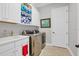 Well-equipped laundry room with front load washer and dryer, utility sink, and storage at 15024 Castle Park Ter, Lakewood Ranch, FL 34202