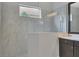 Bright walk-in shower with marble tile and glass enclosure, offering a luxurious and modern spa-like experience at 15024 Castle Park Ter, Lakewood Ranch, FL 34202