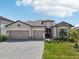 Beautiful single-story home featuring a three-car garage, well-manicured lawn, and stylish stone accents at 15104 Blue Bay Ter, Lakewood Ranch, FL 34211