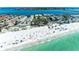 Breathtaking aerial view of the coast with turquoise water and a lively beach with sunbathers and umbrellas at 1603 Gulf Dr N # 6, Bradenton Beach, FL 34217