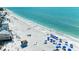 Scenic aerial view of a white sand beach with clear blue water and blue umbrellas at 1603 Gulf Dr N # 6, Bradenton Beach, FL 34217
