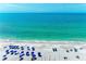Aerial view of a serene beach, featuring blue umbrellas and clear turquoise water on a sunny day at 1603 Gulf Dr N # 6, Bradenton Beach, FL 34217