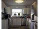 Bright kitchen with stainless steel appliances, white cabinets, and wood grain vinyl flooring at 1750 Gold Ave, Sarasota, FL 34235