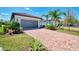 Inviting home showcasing a brick driveway, a gray garage door, and well-maintained lawn with green landscaping at 17714 Northwood Pl, Bradenton, FL 34202