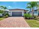 Charming home featuring a red brick driveway, gray garage door, and manicured landscaping with lush bushes at 17714 Northwood Pl, Bradenton, FL 34202