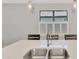 Kitchen island with white countertop, stainless steel sink, and seating in a bright kitchen at 17714 Northwood Pl, Bradenton, FL 34202