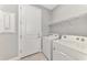 Functional laundry room featuring a door, shelving, and a white washer and dryer at 17714 Northwood Pl, Bradenton, FL 34202