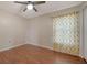 This bedroom features hardwood flooring, a ceiling fan, and a bright window with golden patterned curtains at 2385 Tall Oak Ct, Sarasota, FL 34232
